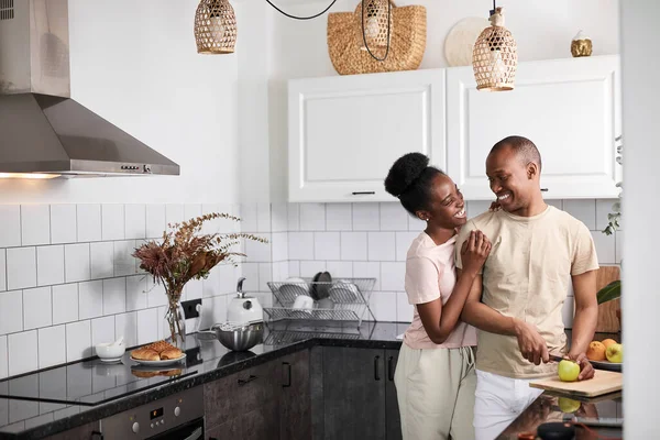 Мила чорна жінка обіймає чоловіка ззаду на кухні — стокове фото