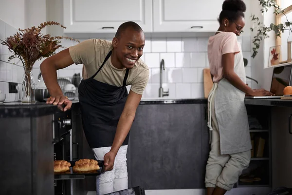 Fekete ember kiveszi a süteményt a sütőből, néz ki, hogy készen áll-e vagy sem — Stock Fotó