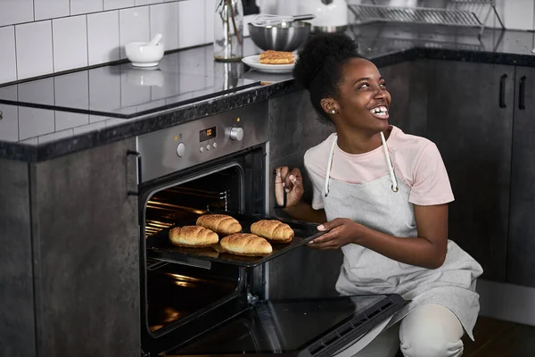 Mignonne femme africaine montre les croissants qu'elle a cuits au four — Photo