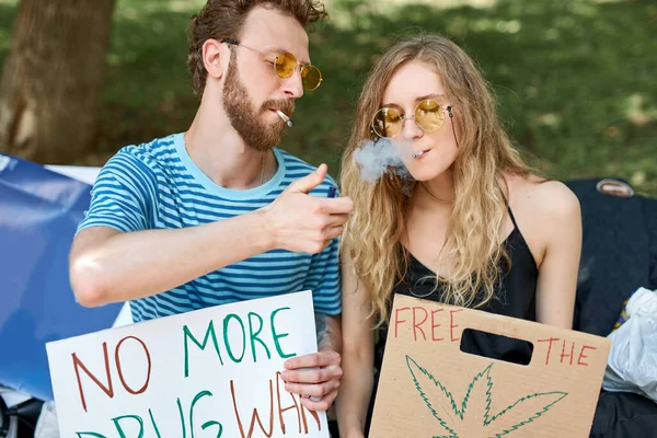 Ung skäggig man hjälper flickvän att tända en cigarett — Stockfoto