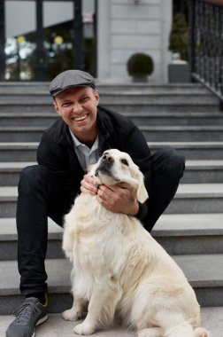 Yakışıklı, gülümseyen adam ve kameraya bakan güzel köpek.