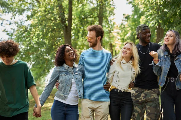 Fröhliche, vielfältige Menschen gehen gemeinsam im Park spazieren — Stockfoto