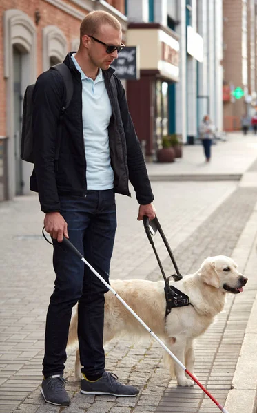 Joven ciego con palo y perro guía paseando — Foto de Stock