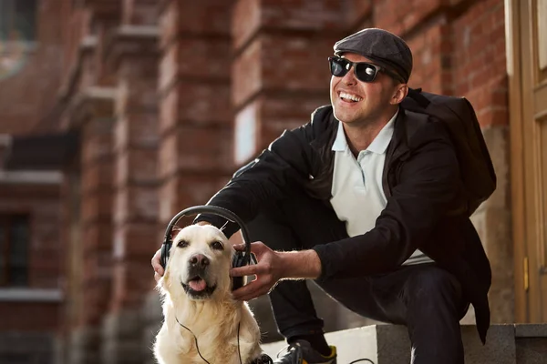Happy blind male entertains his guide dog — Stock Photo, Image