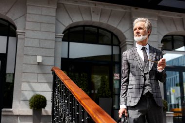 Ofis binasının yakınındaki düşünceli, sakallı, beyaz iş adamı.
