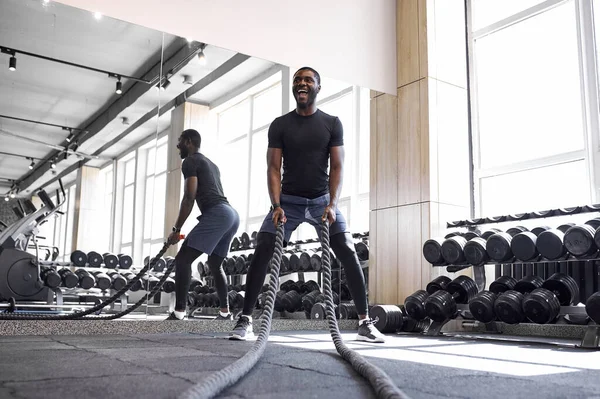 Hombre afroamericano haciendo ejercicios de cuerda de batalla en gimnasio de fitness —  Fotos de Stock