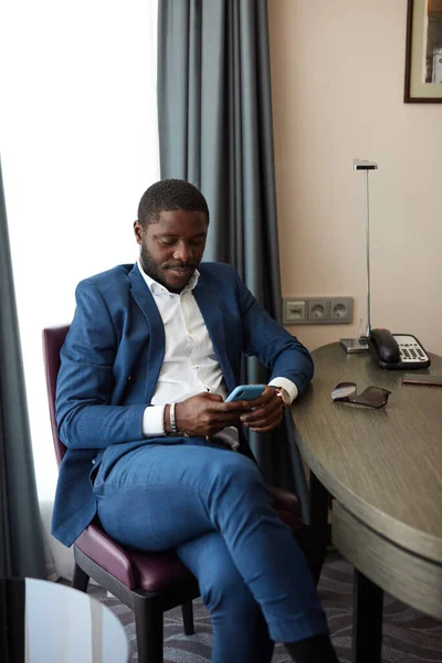 Fiatal afrikai üzletember ül széken a szállodában — Stock Fotó