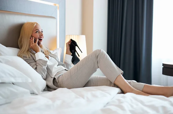 Good-looking blonde female lie on bed and talk on phone — Stock Photo, Image