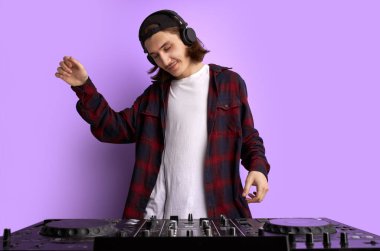 pozitif erkek DJ mor arkaplanda müzik çalıyor