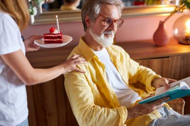 Sevimli küçük kız büyükbabaya doğum günü pastası ikram ediyor.