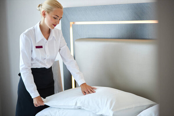 nice maid prepares a bed for guests