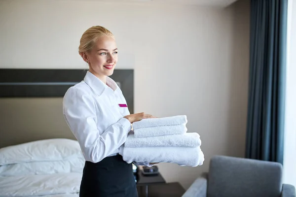 Good-looking maid with white linen and towels in her hands — Stock Photo, Image