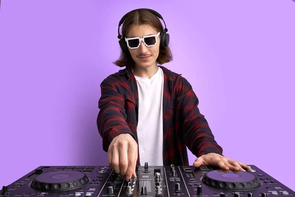 Dj man in white headphones behind dj console, makes song with dj controller. — Stock Photo, Image