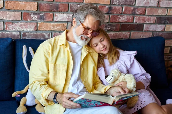 Homem sênior e menina olhando para o álbum de fotos da família na sala de estar — Fotografia de Stock