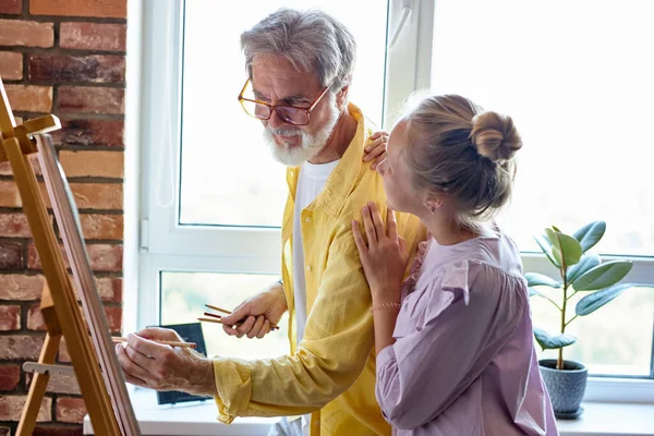 Senior man, grootvader en zijn kleindochter tekenen, samen schilderen — Stockfoto