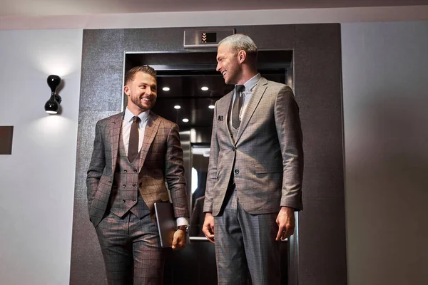 two businessmen have talk in elevator