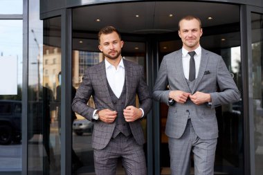 İki iş adamı ceketin düğmelerini ilikler.