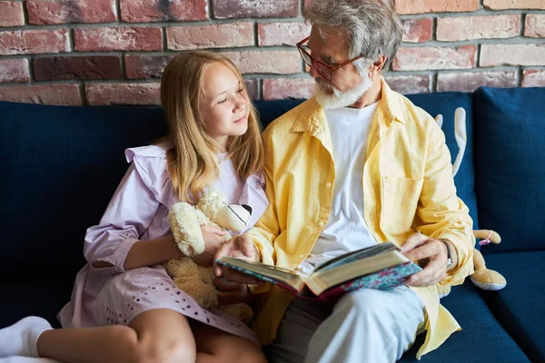 Vriendelijke opa lees boek met kleindochter — Stockfoto