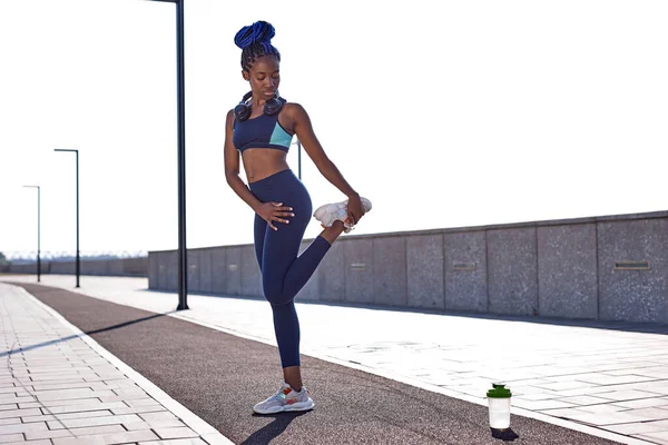 アスリートアフロ女性屋外ランニング中にハムストリングレッグの筋肉を伸ばす — ストック写真