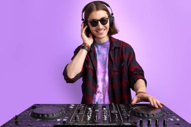 pozitif erkek DJ mor arkaplanda müzik çalıyor