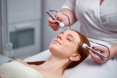 Kozmetik kliniğinde yüz ameliyatı sırasında bir hastayla birlikte güzellik uzmanı.