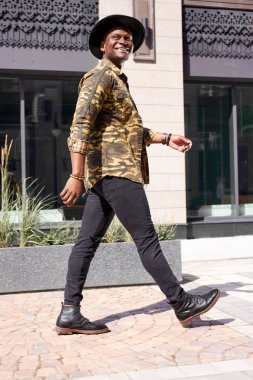 Şehirde yürüyen mutlu Afrikalı bir adamın portresi.