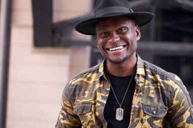 Yakışıklı moda siyahi adam modern şehir binasına karşı poz veriyor.