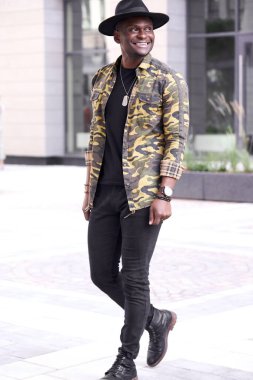 Şehirde yürüyen mutlu Afrikalı bir adamın portresi.