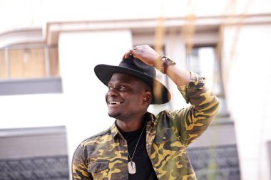 Yakışıklı moda siyahi adam modern şehir binasına karşı poz veriyor.