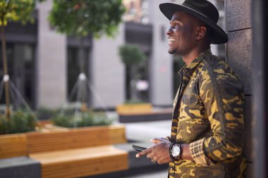 Koyu tenli genç erkek büyük kasabada yalnız yürüyor.