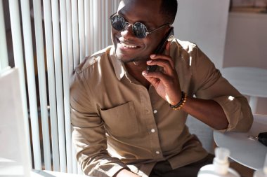 İyi görünümlü Afrikalı bir adam kafeteryada vakit geçirmekten zevk alıyor.