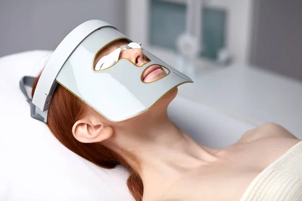 Frau in LED-Maske erhält Hautverjüngungstherapie in ästhetischer Klinik — Stockfoto