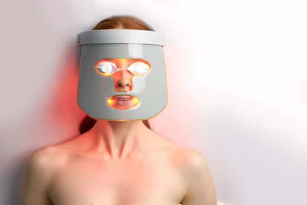 Kvinna i LED mask, få hudföryngring terapi i estetisk klinik — Stockfoto