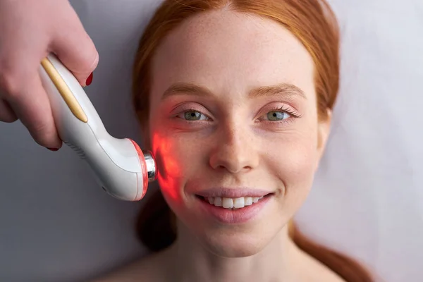 Impresionante mujer que recibe estimulante tratamiento facial eléctrico en el salón de spa — Foto de Stock