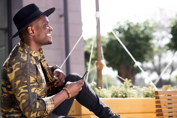 Hombre africano satisfecho usando el teléfono inteligente en la calle — Foto de Stock