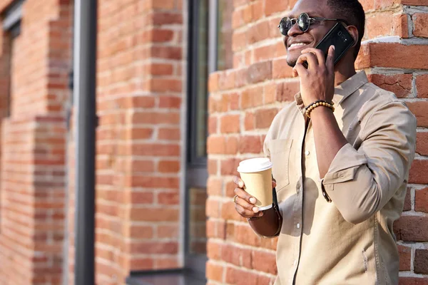 Темнокожий черный мужчина в повседневной одежде ходит и разговаривает по телефону — стоковое фото