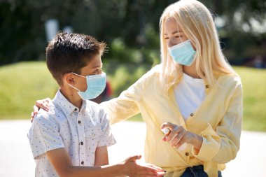 mother and child use disinfectant outdoors clipart