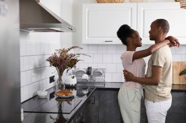 Güzel, mutlu, evli çift mutfakta dans ediyor.