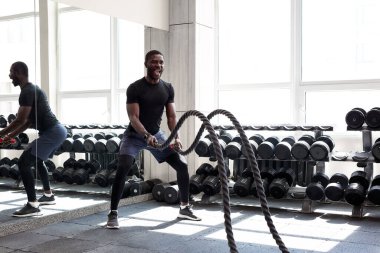 Afrikalı sporcu spor salonunda halat egzersizi yapıyor.