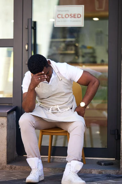 Homem perturbado sentado na rua, sua loja de café está batendo — Fotografia de Stock