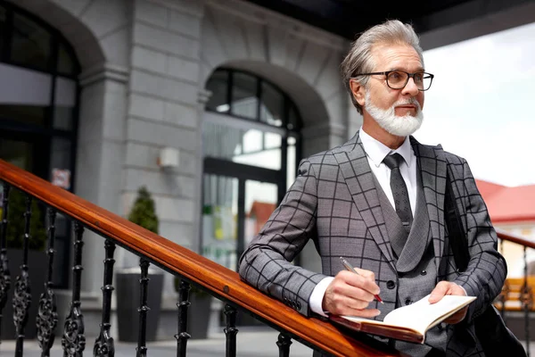 stylish senior man writer make note in notebook after business meeting