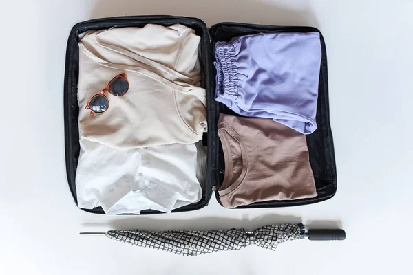 open suitcase with female clothes for trip on white background