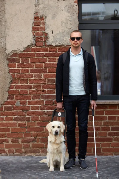 portrait of young caucasian blind man with dog guide