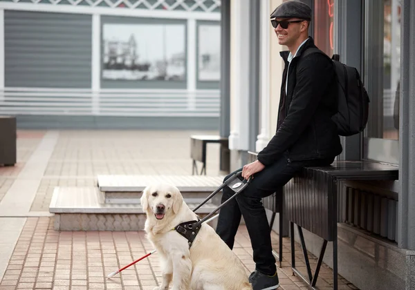 handsome blind guy have rest with golden retriever