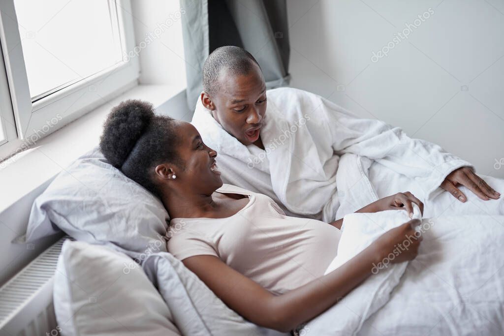 black afroamerican man suprisingly looks at pregnant wifes belly