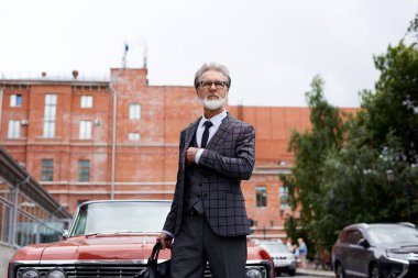 Gri saçlı ve sakallı zarif son sınıf öğrencisi dışarıda çantasıyla dolaşıyor.