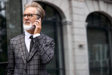 Üst düzey işadamı modern cep telefonuyla konuşmak için ofis binasını terk etti.