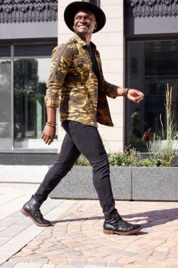 Şehirde yürüyen mutlu Afrikalı bir adamın portresi.