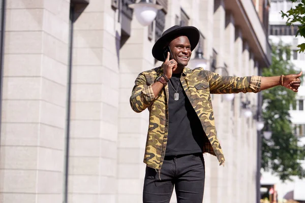 Şık bir Afrikalı adam taksiyi bekliyor ve telefonda konuşuyor.