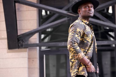 Afro-Amerikan ünlü adam şehrin sokaklarında şık kıyafetler giyerek yürüyor.